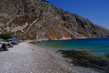 İnsanlar 1 Ağustos 2022 'de Yunanistan' ın Symi Dodecanese plajında güneş ve denizin keyfini çıkarıyorlar..