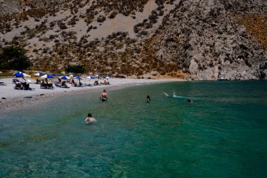 İnsanlar 1 Ağustos 2022 'de Yunanistan' ın Symi Dodecanese plajında güneş ve denizin keyfini çıkarıyorlar..