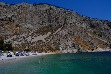 İnsanlar 1 Ağustos 2022 'de Yunanistan' ın Symi Dodecanese plajında güneş ve denizin keyfini çıkarıyorlar..