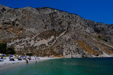 İnsanlar 1 Ağustos 2022 'de Yunanistan' ın Symi Dodecanese plajında güneş ve denizin keyfini çıkarıyorlar..