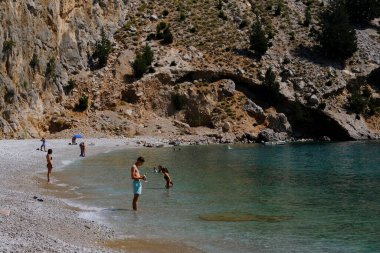 Yunanistan 'ın Symi kentindeki Agios Dimitrios plajında 4 Ağustos 2022' de insanlar güneş ve denizin keyfini çıkarıyorlar..