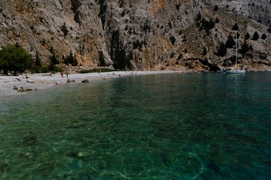 Yunanistan 'ın Symi kentindeki Agios Dimitrios plajında 4 Ağustos 2022' de insanlar güneş ve denizin keyfini çıkarıyorlar..