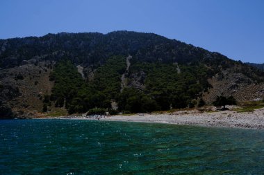 İnsanlar 1 Ağustos 2022 'de Yunanistan' ın Suriye adasındaki plajda güneş ve denizin keyfini çıkarıyorlar..