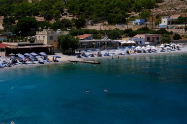 İnsanlar 1 Ağustos 2022 'de Yunanistan' ın Suriye adasındaki plajda güneş ve denizin keyfini çıkarıyorlar..