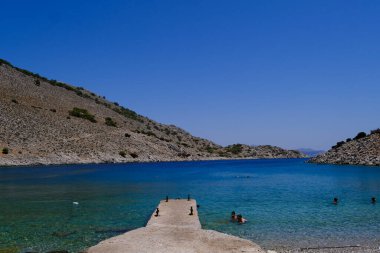 İnsanlar 1 Ağustos 2022 'de Yunanistan' ın Suriye adasındaki plajda güneş ve denizin keyfini çıkarıyorlar..