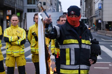 A firefighter lights a banner on fire as he protests with other emergency personnel for better working conditions during a demonstration in Brussels, Belgium on Jan. 27, 2023.