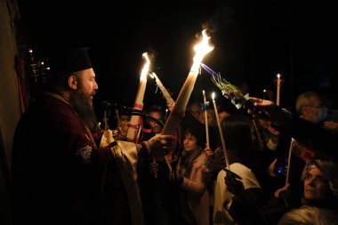 15 Nisan 2023 'te Yunanistan' ın Atina kentindeki Aziz George kilisesinde düzenlenen Paskalya ayini sırasında Ortodoks Hıristiyan rahip mum tutuyor..