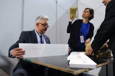 Belçika 'nın Brüksel kentindeki bir sandık merkezinde 29 Nisan 2023' te yapılan Türkiye Cumhurbaşkanlığı ve Genel Seçimleri sırasında bir seçim görevlisi oy pusulalarını hazırlıyor..