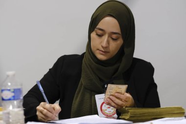 Belçika 'nın Brüksel kentindeki bir sandık merkezinde 29 Nisan 2023' te yapılan Türkiye Cumhurbaşkanlığı ve Genel Seçimleri sırasında bir seçim görevlisi oy pusulalarını hazırlıyor..
