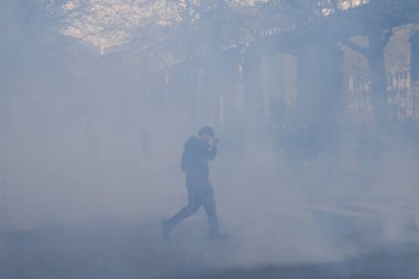 Maskeli protestocular, 6 Nisan 2023 'te Fransa' nın Paris kentinde düzenlenen gösterinin sonunda çevik kuvvet polisiyle yaşanan çatışmalar sırasında göz yaşartıcı gaz patlamasıyla tepki verdiler..