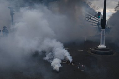 Maskeli protestocular, 6 Nisan 2023 'te Fransa' nın Paris kentinde düzenlenen gösterinin sonunda çevik kuvvet polisiyle yaşanan çatışmalar sırasında göz yaşartıcı gaz patlamasıyla tepki verdiler..