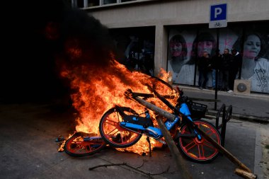 Maskeli protestocular, 6 Nisan 2023 'te Fransa' nın Paris kentinde düzenlenen bir gösteride meydana gelen çatışmalar sırasında çöp bidonları ve motosikletleri ateşe verdiler..