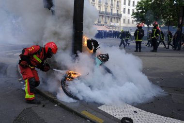 Paris, Fransa. 1 Mayıs 2023. İşçi sendikası yürüyüşü sırasında çıkan yangını söndürmeye çalışan itfaiyeciler görülüyor..