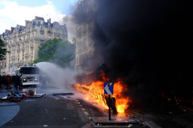 Su Topu, Fransa 'nın 1 Mayıs 2023 tarihli Paris' teki Fransız emeklilik reformuna karşı düzenlenen bir gösteri sırasında yanan scooterlara su püskürttü..
