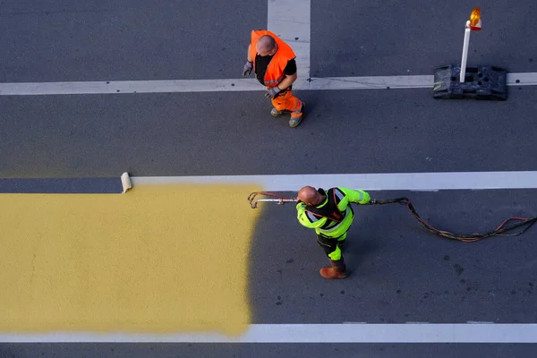 stock image A municipal  worker using a paint sprayer applies yellow road markings to a crosswalk in Brussels, Belgium on July 4th 2023.