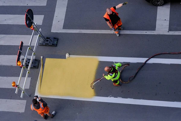 stock image A municipal  worker using a paint sprayer applies yellow road markings to a crosswalk in Brussels, Belgium on July 4th 2023.