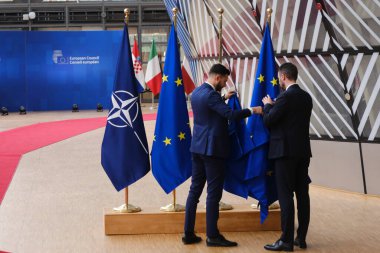 Belçika 'nın Brüksel kentindeki Avrupa Karargahında 29 Haziran 2023' te AB ve NATO bayraklarını düzelten bir yetkili görülüyor.