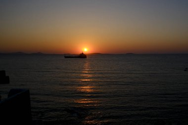 7 Temmuz 2023 'te Yunanistan' ın Naxos limanında gün batımında yola çıkan bir kargo gemisi.