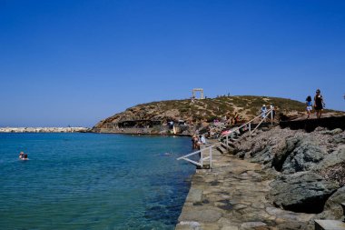 İnsanlar 10 Temmuz 2023 'te Yunanistan' ın Naxos limanında güneşlenip yüzüyorlar.