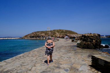 9 Temmuz 2023 'te Yunanistan' ın Naxos adasındaki Delian Apollo antik tapınağının kalıntıları önünde yürüyen insanlar görülüyor..