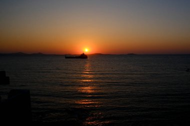 7 Temmuz 2023 'te Yunanistan' ın Naxos limanında gün batımında yola çıkan bir kargo gemisi.