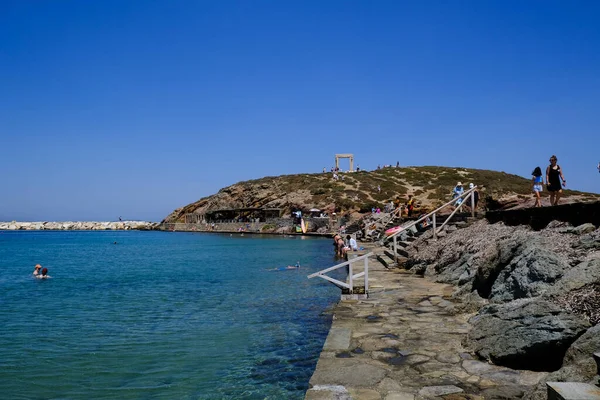 İnsanlar 10 Temmuz 2023 'te Yunanistan' ın Naxos limanında güneşlenip yüzüyorlar.