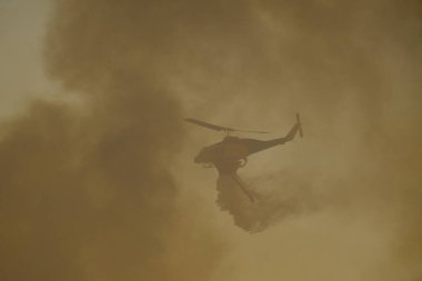 Yunanistan 'ın Atina banliyösünde 22 Ağustos 2023' te bir yangın söndürme helikopteri su düşürdü.