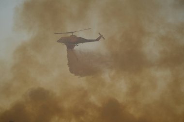 Yunanistan 'ın Atina banliyösünde 22 Ağustos 2023' te bir yangın söndürme helikopteri su düşürdü.