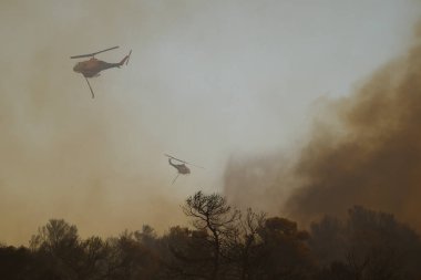 Yunanistan 'ın Atina banliyösünde 22 Ağustos 2023' te bir yangın söndürme helikopteri su düşürdü.