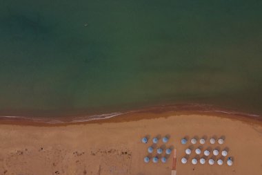 24 Ağustos 2023 'te Yunanistan' ın Kourouta plajında güneşli bir günde güneşlik ve şemsiye manzarası.