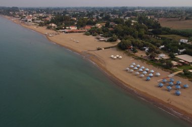 24 Ağustos 2023 'te Yunanistan' ın Kourouta plajında güneşli bir günde güneşlik ve şemsiye manzarası.