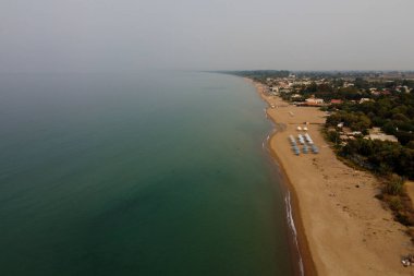 24 Ağustos 2023 'te Yunanistan' ın Kourouta plajında güneşli bir günde güneşlik ve şemsiye manzarası.