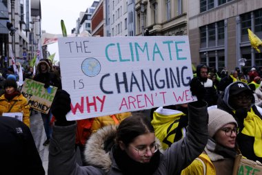 Bir gösterici, COP28 'in 3 Aralık 2023' te Brüksel, Belçika 'da Dubai' de düzenlenen bir iklim protestosu sırasında bir pankart tutuyor..