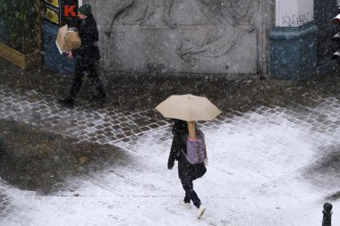 17 Ocak 2024 'te Brüksel' in merkezinde yoğun kar yağışı sırasında insanlar yürür.