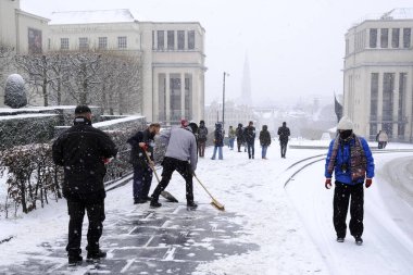 İşçiler, 17 Ocak 2024 'te Belçika' da yoğun bir kar yağışı sırasında Brüksel 'in orta kesimindeki sokakları temizliyorlar..