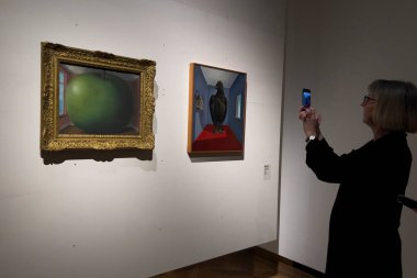 Visitors look at paintings of surrealist artists during the exhibition 