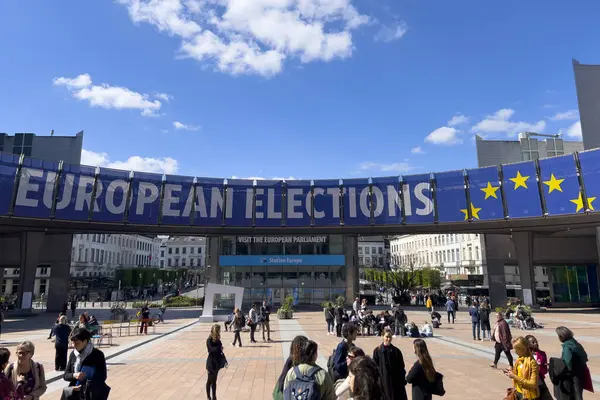 stock image People walk toward a banner advertising the European elections outside the European Parliament  in Brussels, Belgium on April 10, 2024.