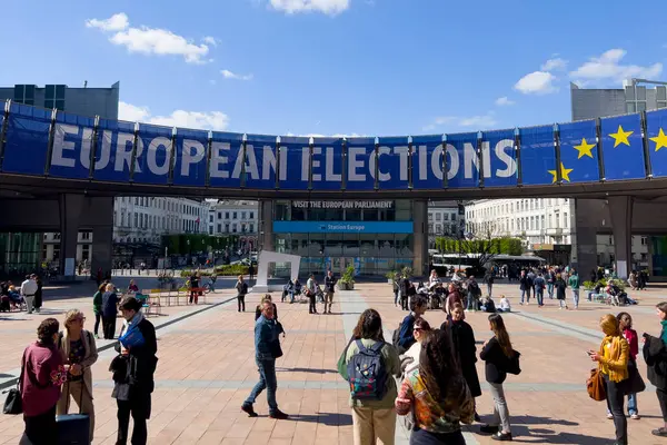 stock image People walk toward a banner advertising the European elections outside the European Parliament  in Brussels, Belgium on April 10, 2024.