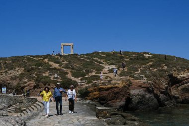 Yunanistan 'ın Naxos Adası' ndaki Delian Apollo antik tapınağının yıkıntıları önünde 3 Mayıs 2024 'te insanlar yürüyor.