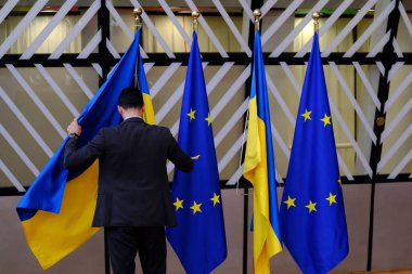 Bir adam Avrupa Birliği bayrağının yanına 27 Haziran 2024 'te Brüksel' de yapılan Avrupa Birliği zirvesinin ilk gününde bir Ukrayna bayrağı koydu..