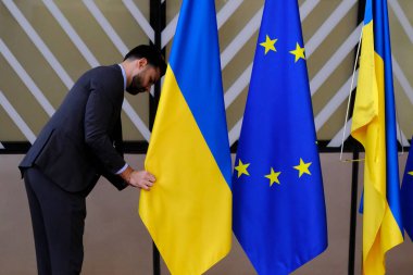 Bir adam Avrupa Birliği bayrağının yanına 27 Haziran 2024 'te Brüksel' de yapılan Avrupa Birliği zirvesinin ilk gününde bir Ukrayna bayrağı koydu..