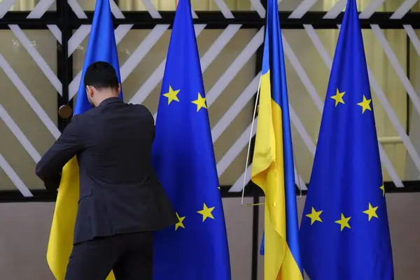 stock image A man puts a Ukrainian flag next to a European Union flag, on the first day of a European Union leaders' summit in Brussels, Belgium June 27, 2024.