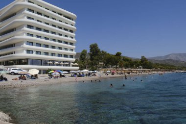 Yunanistan 'ın Moreloponnese kentindeki Agioi Theodoroi plajındaki lüks otelin önünde 23 Ağustos 2024' te insanlar denizin keyfini çıkarıyorlar..