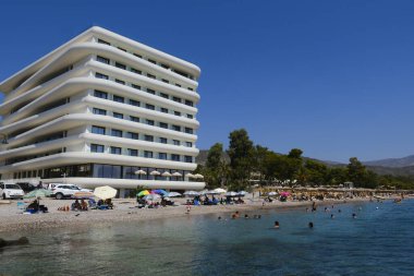 Yunanistan 'ın Moreloponnese kentindeki Agioi Theodoroi plajındaki lüks otelin önünde 23 Ağustos 2024' te insanlar denizin keyfini çıkarıyorlar..
