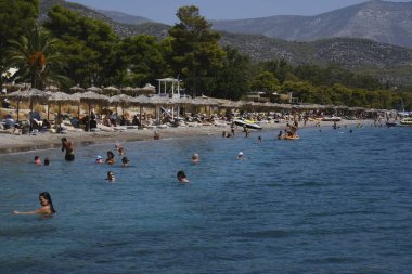 Yunanistan 'ın Moreloponnese kentindeki sıcak bir yaz gününde 23 Ağustos 2024' te Agioi Theodoroi plajında insanlar serinliyor..