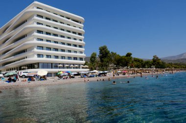 Yunanistan 'ın Moreloponnese kentindeki Agioi Theodoroi plajındaki lüks otelin önünde 23 Ağustos 2024' te insanlar denizin keyfini çıkarıyorlar..