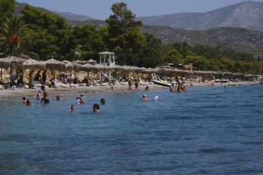 Yunanistan 'ın Moreloponnese kentindeki sıcak bir yaz gününde 23 Ağustos 2024' te Agioi Theodoroi plajında insanlar serinliyor..