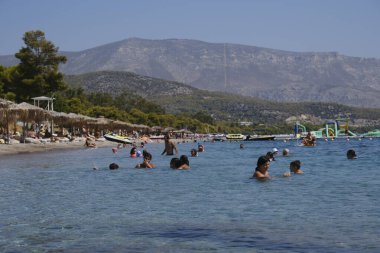 Yunanistan 'ın Moreloponnese kentindeki sıcak bir yaz gününde 23 Ağustos 2024' te Agioi Theodoroi plajında insanlar serinliyor..