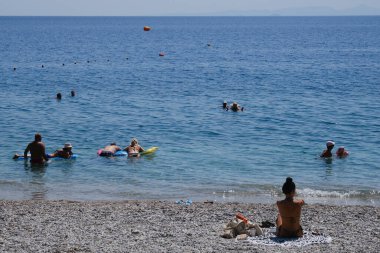 Yunanistan 'ın Moreloponnese kentindeki sıcak bir yaz gününde 23 Ağustos 2024' te Agioi Theodoroi plajında insanlar serinliyor..