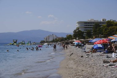 İnsanlar güneşli bir yaz gününde Yunanistan 'ın Mora kıyısındaki Agioi Theodoroi plajında güneşleniyorlar..